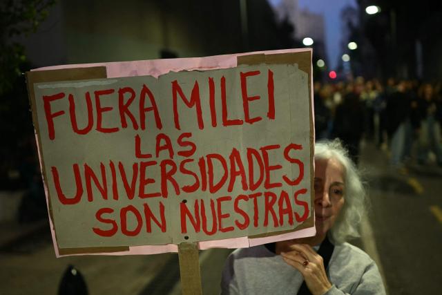 A woman holds a banner reading 'Get out Milei from the universities, they are ours' during a protest organized by university students and workers against the Javier Milei government's policies in Buenos Aires on May 12, 2026. (Photo by Luis ROBAYO / AFP)