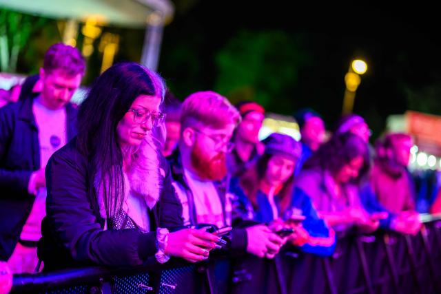 Spectators vote on their mobile phones during the voting round for the final at the fan area at City Hall Square (Rathausplatz) during the first semi-final of the Eurovision Song Contest (ESC) in Vienna, Austria on May 12, 2026. (Photo by MAX SLOVENCIK / APA / AFP) / Austria OUT