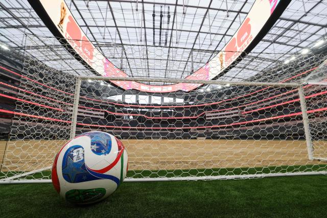 A giant ball is displayed behind a goal as an expanded pitch surface area, which required the removal of corner seating and a raised custom field platform, awaits the installation of grass during the 30 Days to FIFA World Cup 2026 media event at SoFI Stadium before the pitch installation and temporary renaming to Los Angeles Stadium in Inglewood, California on May 12, 2026. The US Men's National Team will play their first 2026 FIFA World Cup match on June 12 against Paraguay. (Photo by Patrick T. Fallon / AFP)
