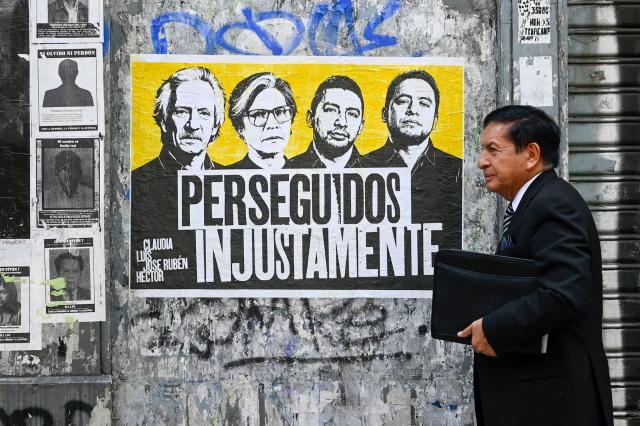 A man walks past a sign tha reads 'unjustly persecuted' featuring Guatemalan journalist and founder of the former newspaper 'El Periodico', Jose Ruben Zamora (L), Guatemalan former lawyer of the International Commission against Impunity in Guatemala (CICIG), Claudia Gonzalez (2nd L) and Maya leaders Luis Pacheco and Hector Chaclan in a street of Guatemala City on May 12, 2026. (Photo by Johan ORDONEZ / AFP)