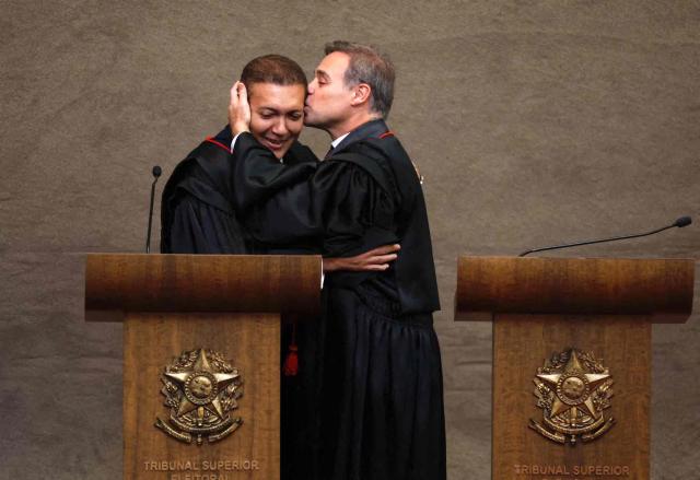 The new Vice President of the Superior Electoral Court, Minister Andre Mendonca, kisses Judge Nunes Marques, President of the Superior Electoral Court (TSE), during Nunes's swearing-in ceremony in Brasilia on May 12, 2026. (Photo by Sergio LIMA / AFP)