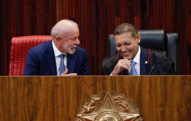 Brazil's President Luiz Inacio Lula da Silva (L) speaks with Judge Nunes Marques, President of the Superior Electoral Court (TSE), during Nunes's swearing-in ceremony in Brasilia on May 12, 2026. (Photo by Sergio LIMA / AFP)