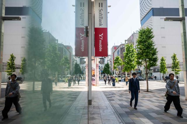 People walk past a Softbank store in Tokyo on May 13, 2026. (Photo by Andrew CABALLERO-REYNOLDS / AFP)