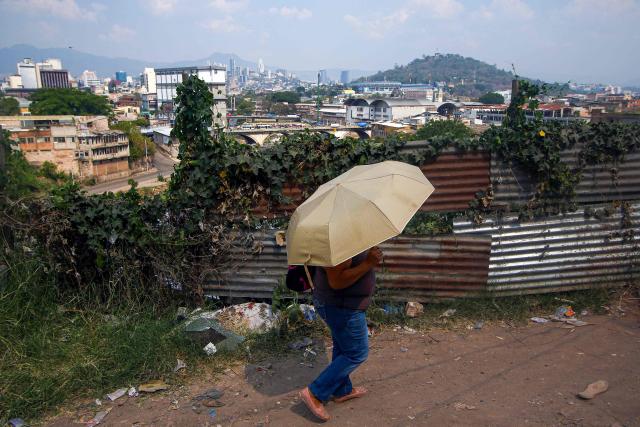 A woman covers herself from the sun with an umbrella in Tegucigalpa City on May 12, 2026. Honduras has decided to shorten the school-day and hold virtual classes due to the high temperatures that could intensify due to El Nino phenomenon, official sources reported. (Photo by Johny MAGALLANES / AFP)