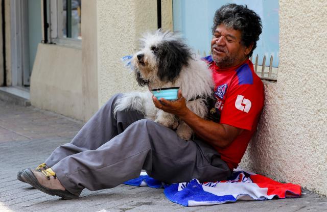 A man gives water to his dog during a heatwave in Tegucigalpa City on May 11, 2026. Honduras has decided to shorten the school-day and hold virtual classes due to the high temperatures that could intensify due to El Nino phenomenon, official sources reported. (Photo by Johny MAGALLANES / AFP)