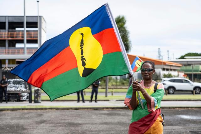 A pro-independence activist waves a flag during a demonstration to mark the second anniversary of the spring 2024 riots in Noumea, in the French overseas collectivity of New Caledonia, on May 13, 2026. Two years after the violence that left 14 dead and caused several billion euros’ worth of damage in New Caledonia, tensions and mistrust remain, as the debate over the electoral roll, which sparked the insurrectional crisis, is still unresolved. (Photo by Delphine MAYEUR / AFP)