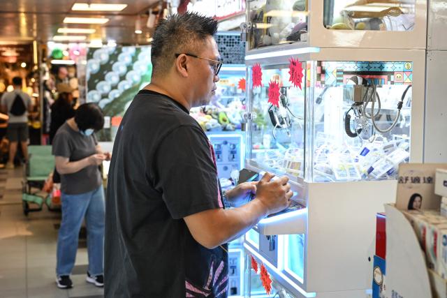 A photo taken on May 11, 2026 shows a customer using a claw machine in an arcade centre at a shopping mall in Hong Kong. Authorities have proposed tightening the regulation of claw machine arcades by proposing a licensing program to curb potential addiction risks. (Photo by Peter PARKS / AFP)