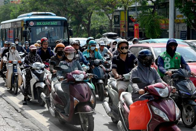 People ride motorbikes and scooters along a street in Hanoi on May 13, 2026. (Photo by Nhac NGUYEN / AFP)