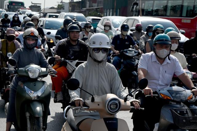 People ride motorbikes and scooters along a street in Hanoi on May 13, 2026. (Photo by Nhac NGUYEN / AFP)