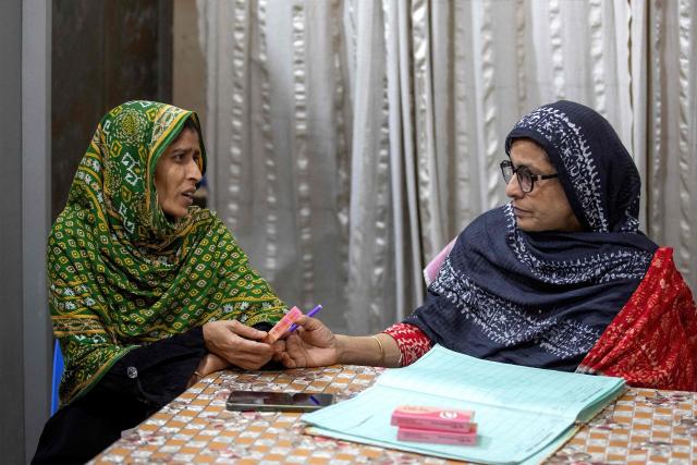 This photograph taken on April 27, 2026 shows Tahmina (R), a family welfare officer giving  birth control pills to a woman at the Savar Upazila Health Complex in Dhaka. Bangladesh's once-praised family planning system is buckling under severe contraceptive shortages, raising fears of a rise in unplanned pregnancies in one of the world's most densely populated countries. (Photo by Salahuddin Ahmed / AFP)