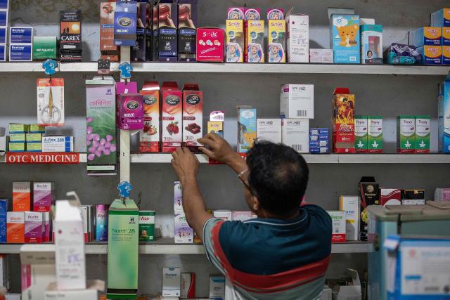 This photograph taken on April 27, 2026 shows a worker arranging packets of condoms at a pharmacy in Dhaka. Bangladesh's once-praised family planning system is buckling under severe contraceptive shortages, raising fears of a rise in unplanned pregnancies in one of the world's most densely populated countries. (Photo by Salahuddin Ahmed / AFP)