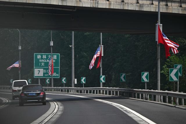 The national flags of the United States and China hang on a highway, on May 13, 2026, ahead of a visit by US President Donald Trump. (Photo by Pedro PARDO / AFP)