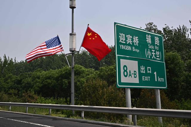 The national flags of the United States and China hang on a highway, on May 13, 2026, ahead of a visit by US President Donald Trump. (Photo by Pedro PARDO / AFP)