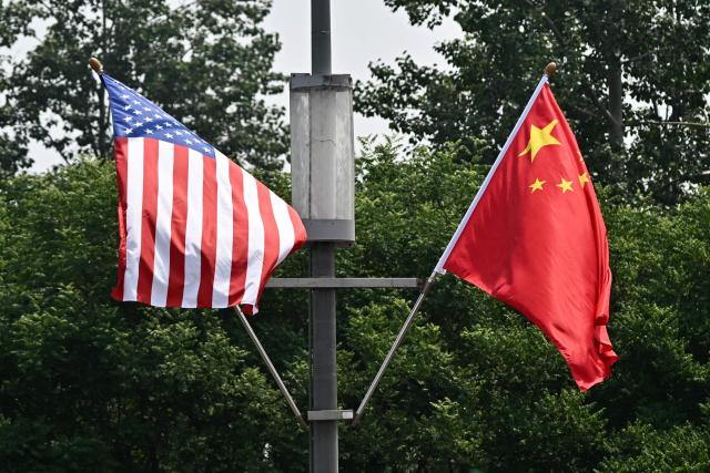 The national flags of the United States and China hang on a highway, on May 13, 2026, ahead of a visit by US President Donald Trump. (Photo by Pedro PARDO / AFP)