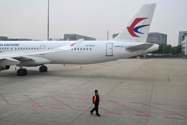 A worker walks next an aircraft of China Eastern Airlines at the Shanghai Hongqiao International Airport in Shanghai on May 12, 2026. (Photo by Hector RETAMAL / AFP)