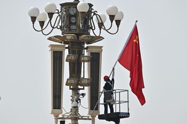A worker removes a Chinese flag from Tiananmen Square in Beijing on May 13, 2026, ahead of a visit by US President Donald Trump. (Photo by Pedro PARDO / AFP)