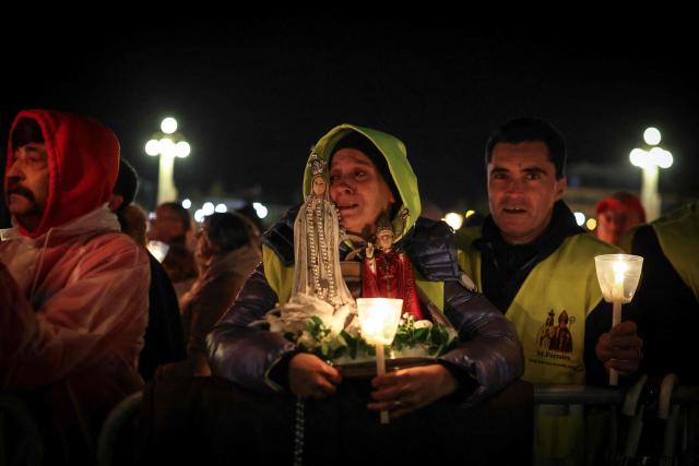 A pilgrim holds a candle and an image of Our Lady Fatima during the candlelight procession at the Shrine of Fatima, central Portugal, late on May 12, 2026. Thousands of pilgrims converged on the Fatima Sanctuary to celebrate the anniversary of Fatima's miracle when three shepherd children claimed to have seen the Virgin Mary in May 1917. (Photo by PATRICIA DE MELO MOREIRA / AFP)