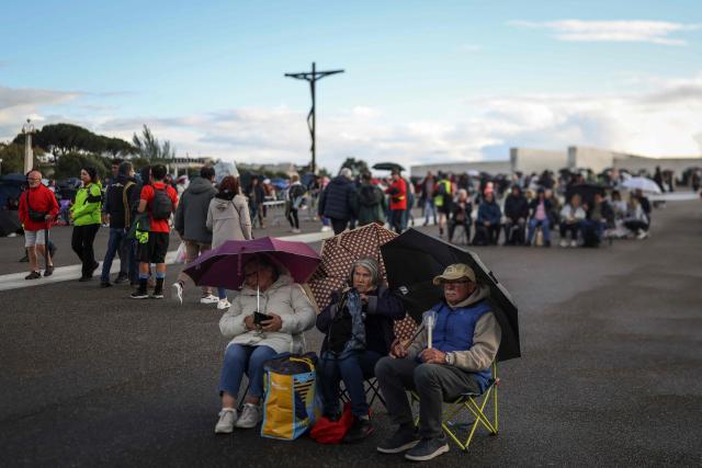 Pilgrims sit and wait for the candlelight procession at the Shrine of Fatima, central Portugal, on May 12, 2026. Thousands of pilgrims converged on the Fatima Sanctuary to celebrate the anniversary of Fatima's miracle when three shepherd children claimed to have seen the Virgin Mary in May 1917. (Photo by PATRICIA DE MELO MOREIRA / AFP)