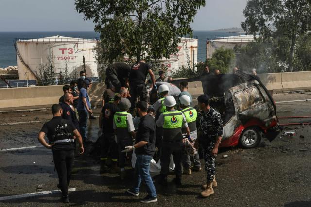 First responders intervene around a vehicle targeted by an Israeli drone strike on a highway near the town of Jiyeh, south of Beirut, on May 13, 2026. Israeli strikes targeted two cars on May 13 on a major highway linking Beirut to southern Lebanon, state media reported, despite a truce in the war between Israel and Hezbollah. (Photo by MAHMOUD ZAYYAT / AFP)