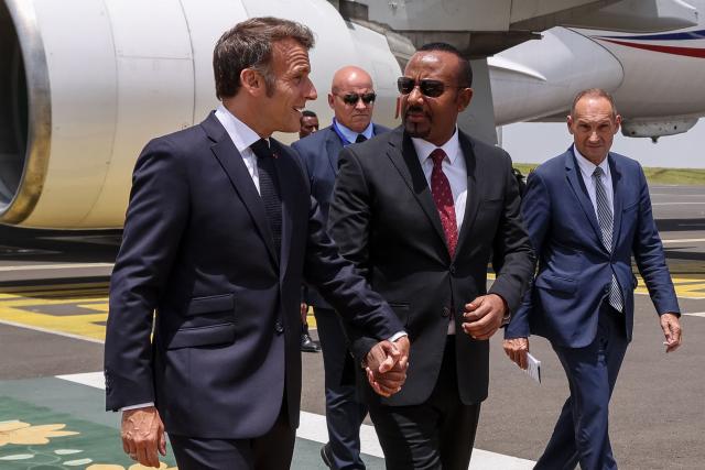 France's President Emmanuel Macron (L) is welcomed by Ethiopia's Prime Minister Abiy Ahmed (C) as he arrives at the Bole International Airport in Addis Ababa on May 13, 2026. (Photo by Ludovic MARIN / AFP) / ALTERNATE CROP