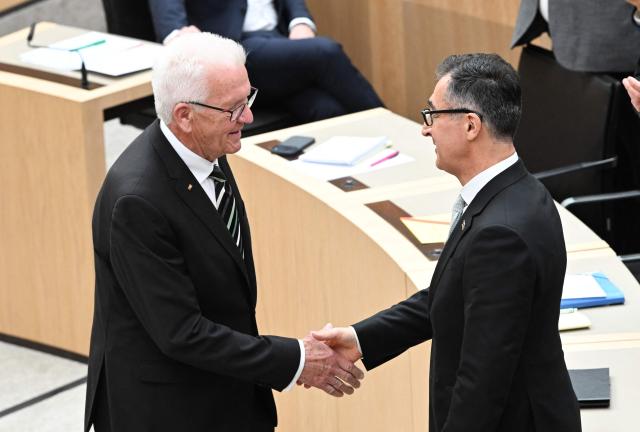 Baden-Wuerttemberg's outgoing State Premier Winfried Kretschmann (L) congratulates his successor Cem Oezdemir of the Greens after he was elected as new State Premier of Baden-Wuerttemberg in the state parliament in Stuttgart, southern Germany, on May 13, 2026. The inaugural session of the new state parliament of Baden-Wuerttemberg took place the day before, on May 12, 2026, following state elections on March 8, 2026. (Photo by THOMAS KIENZLE / AFP)