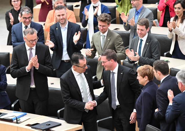 Cem Oezdemir (C-L) of the Greens is congratulated by Manuel Hagel (C-R), chairman of the conservative Christian Democratic Union (CDU) party in Baden-Wuerttemberg, after Oezdemir was elected as new State Premier of Baden-Wuerttemberg in the state parliament in Stuttgart, southern Germany, on May 13, 2026. The inaugural session of the new state parliament of Baden-Wuerttemberg took place the day before, on May 12, 2026, following state elections on March 8, 2026. (Photo by THOMAS KIENZLE / AFP)