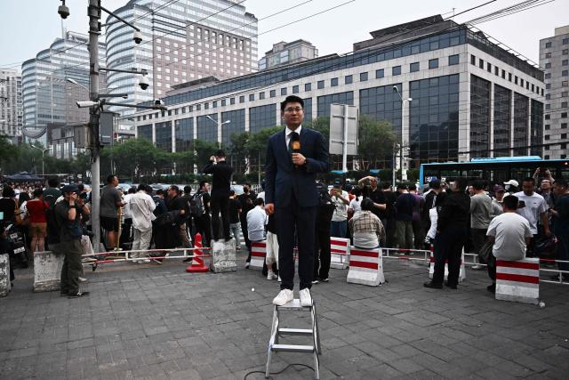 People gather to watch US President Donald Trump's motorcade in Beijing on May 13, 2026. (Photo by Pedro Pardo / AFP)