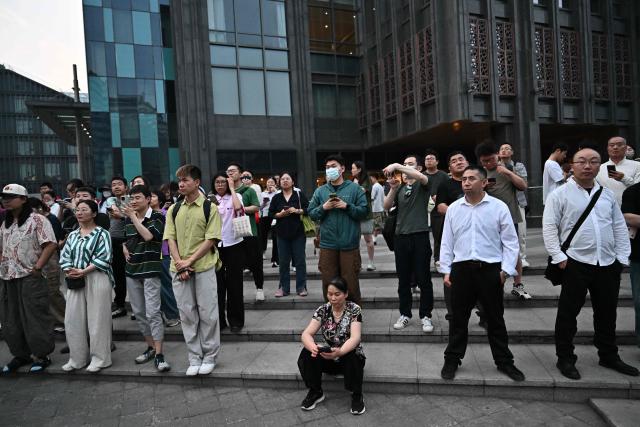 People gather to watch US President Donald Trump's motorcade in Beijing on May 13, 2026. (Photo by Pedro Pardo / AFP)