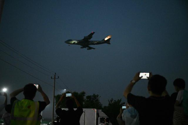 People gather to get a view of Air Force One, carrying US President Donald Trump, arriving at Beijing Capital Airport in Beijing on May 13, 2026. (Photo by GREG BAKER / AFP)