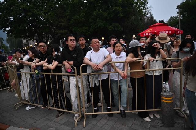 People gather to watch US President Donald Trump's motorcade in Beijing on May 13, 2026. (Photo by Pedro Pardo / AFP)