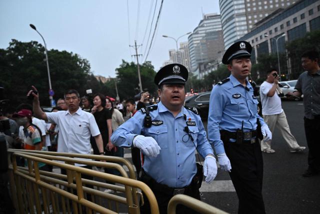 People gather to watch US President Donald Trump's motorcade in Beijing on May 13, 2026. (Photo by Pedro Pardo / AFP)