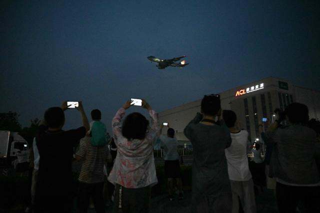 People gather to get a view of Air Force One, carrying US President Donald Trump, arriving at Beijing Capital Airport in Beijing on May 13, 2026. (Photo by GREG BAKER / AFP)