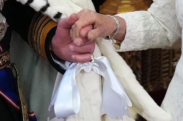 Britain's King Charles III holds Britain's Queen Camilla hand after making his speech in the House of Lords chamber, during the State Opening of Parliament, at the Houses of Parliament, in London on May 13, 2026. (Photo by Kirsty Wigglesworth / POOL / AFP)