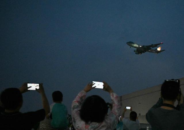 People gather to get a view of Air Force One, carrying US President Donald Trump, arriving at Beijing Capital Airport in Beijing on May 13, 2026. (Photo by GREG BAKER / AFP)