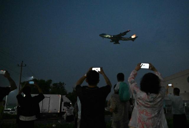 TOPSHOT - People gather to get a view of Air Force One, carrying US President Donald Trump, arriving at Beijing Capital Airport in Beijing on May 13, 2026. (Photo by GREG BAKER / AFP)
