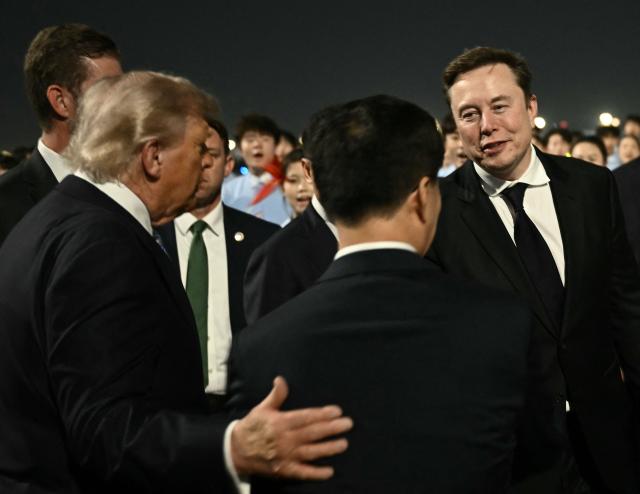 US President Donald Trump (C) presents SpaceX, Twitter and electric car maker Tesla CEO Elon Musk (R) to China’s Vice President Han Zheng at Beijing Capital Airport in Beijing on May 13, 2026. (Photo by Brendan SMIALOWSKI / AFP)