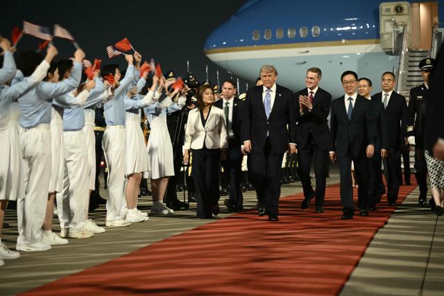 US President Donald Trump (C), US Ambassador To china David Perdue (center-R) escorted by China's Vice President Han Zheng (R) are greeted by Chinese youth upon arriving at Beijing Capital Airport in Beijing on May 13, 2026. (Photo by Brendan SMIALOWSKI / AFP)