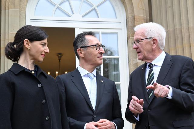 Baden-Wuerttemberg's new State Premier Cem Oezdemir (C) of the Greens, his wife Flavia Zaka (L) and his predecessor Winfried Kretschmann stand on the terrace of Villa Reitzenstein in Stuttgart, southern Germany, after Oezdemir took over the post, on May 13, 2026.  (Photo by Bernd Weißbrod / POOL / AFP)