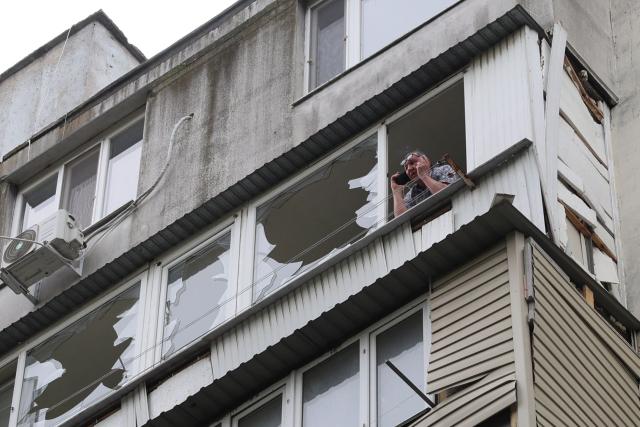 A local resident speaks on a mobile phone while standing on a damaged balcony of a residential building following an air attack in Odesa on May 13, 2026, amid the Russian invasion in Ukraine. (Photo by Oleksandr GIMANOV / AFP)