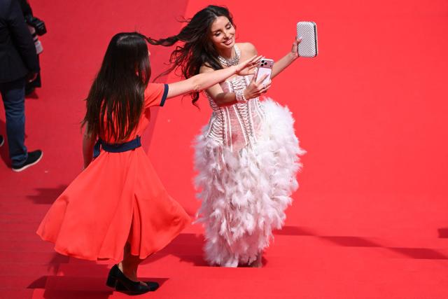 A guest tries to take a selfie as she arrives for the screening of the film "Nagi Notes" at the 79th edition of the Cannes Film Festival in Cannes, southern France on May 13, 2026. (Photo by Antonin THUILLIER / AFP)