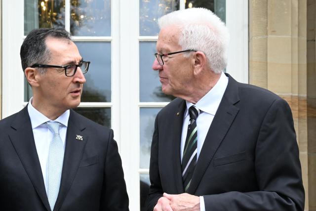 Baden-Wuerttemberg's new State Premier Cem Oezdemir (L) of the Greens and his predecessor Winfried Kretschmann stand on the terrace of Villa Reitzenstein in Stuttgart, southern Germany, after Oezdemir took over the post, on May 13, 2026.  (Photo by Bernd Weißbrod / POOL / AFP)
