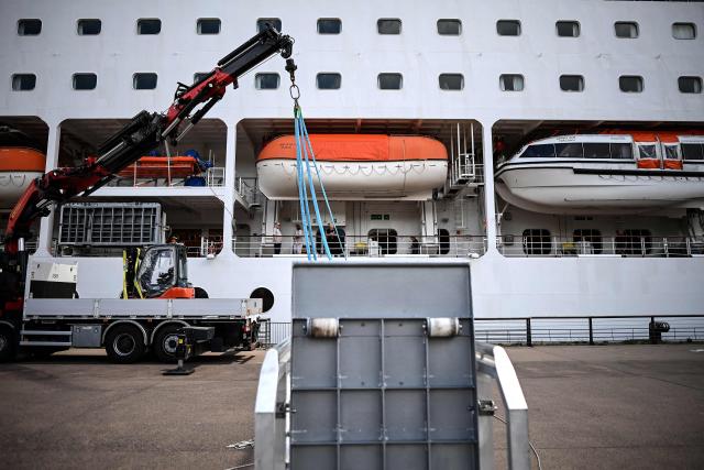 Passengers stand aboard the Bahamas-registered cruise ship Ambition after they were confined following the outbreak of a gastrointestinal illness onboard, at the Bordeaux port in Bordeaux, southwestern France on May 13, 2026. French authorities on May 13 confined more than 1,700 passengers and crew on a British cruise ship docked in Bordeaux after an elderly passenger died, said officials, who played down any links to the hantavirus scare. (Photo by Christophe ARCHAMBAULT / AFP)