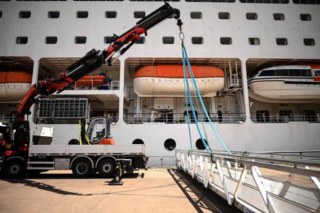 Passengers stand aboard the Bahamas-registered cruise ship Ambition after they were confined following the outbreak of a gastrointestinal illness onboard, at the Bordeaux port in Bordeaux, southwestern France on May 13, 2026. French authorities on May 13 confined more than 1,700 passengers and crew on a British cruise ship docked in Bordeaux after an elderly passenger died, said officials, who played down any links to the hantavirus scare. (Photo by Christophe ARCHAMBAULT / AFP)
