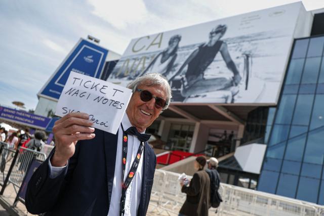 A festival-goer holds up a sign seeking invitations for the red carpet during the 79th edition of the Cannes Film Festival in Cannes, southern France on May 13, 2026. (Photo by SAMEER AL-DOUMY / AFP)