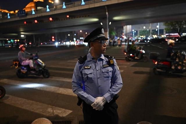 A police officer stands guard before the passage of US President Donald Trump's motorcade in Beijing on May 13, 2026. (Photo by Pedro PARDO / AFP)
