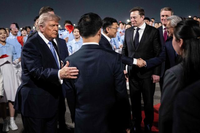 US President Donald J. Trump watches as members of his delegation, including Tesla and SpaceX's CEO Elon Musk and Nvidia President and CEO Jensen Huang, are greeted by China's Vice President Han Zheng and others as they arrive at the Beijing Capital International Airport on May 13, 2026. (Photo by Brendan SMIALOWSKI / AFP)