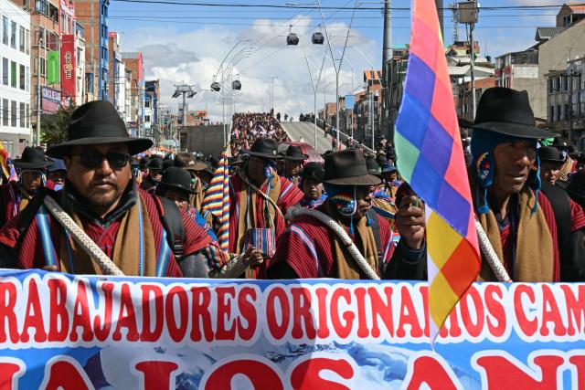 Indigenous people from the "Ponchos Rojos" union march from El Alto to La Paz during a protest against the government of Bolivian President Rodrigo Paz, on May 13, 2026. For the past two weeks, workers, farmers, school teachers, Indigenous groups and transport workers have been pressuring the government. Their demands range from wage increases and economic stabilization to opposition to the privatization of public companies. (Photo by AIZAR RALDES / AFP)
