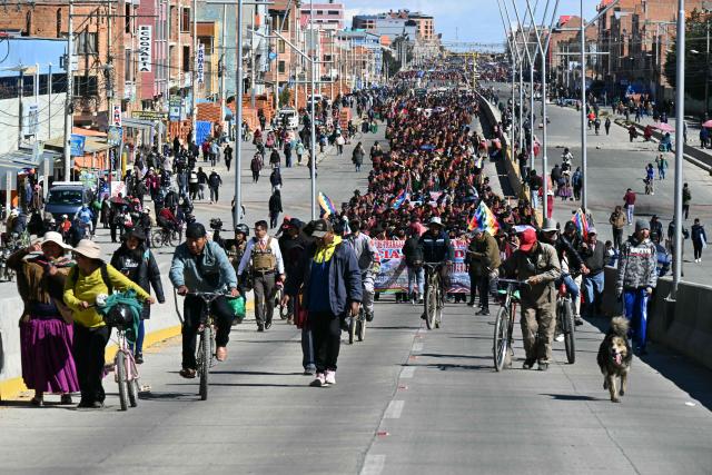 Indigenous people from the "Ponchos Rojos" union march from El Alto to La Paz during a protest against the government of Bolivian President Rodrigo Paz, on May 13, 2026. For the past two weeks, workers, farmers, school teachers, Indigenous groups and transport workers have been pressuring the government. Their demands range from wage increases and economic stabilization to opposition to the privatization of public companies. (Photo by AIZAR RALDES / AFP)