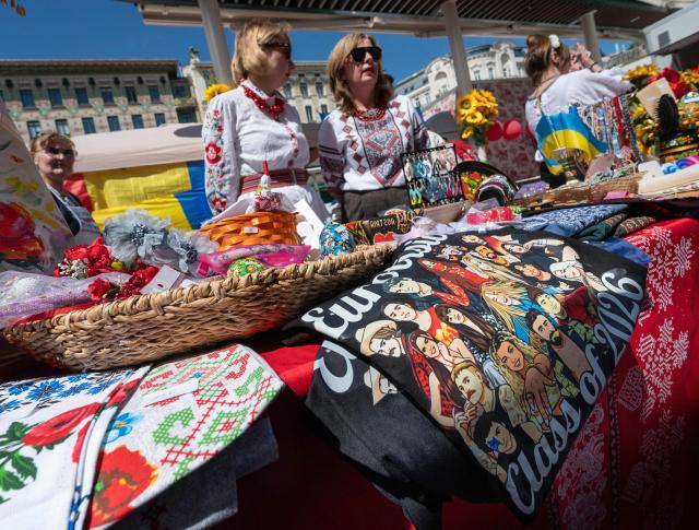 Ukrainian women, dressed in traditional costumes, react during the ESC side event 'Eurovision Market Contest' at Vienna’s Naschmarkt, Austria, where several food and souvenir stalls from different ESC participating countries take part, on May 13, 2026. (Photo by Joe KLAMAR / AFP)