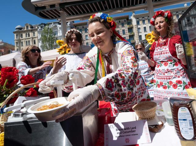 Ukrainian women, dressed in traditional costumes, serve traditional 'Vareniki' during the ESC side event 'Eurovision Market Contest' at Vienna’s Naschmarkt, Austria, where several food and souvenir stalls from different ESC participating countries take part, on May 13, 2026. (Photo by Joe Klamar / AFP)